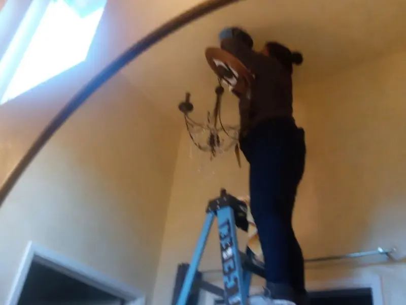 Electrician installing a chandelier in a Millville residence